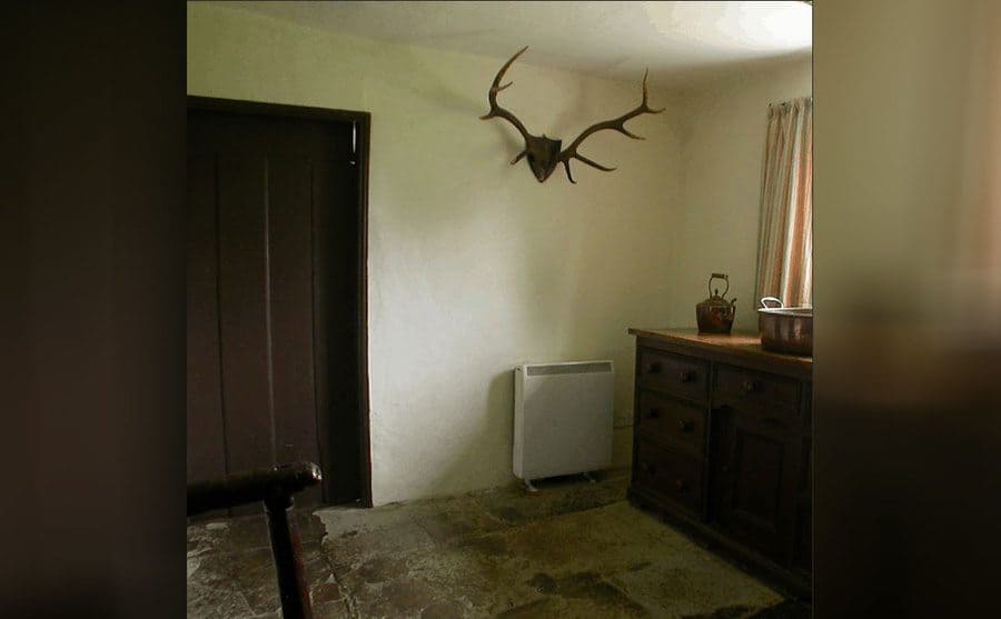 A photograph of an empty room with deer antlers on the wall