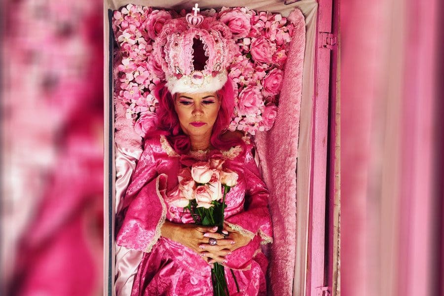 Kitten Kay Sera in all pink surrounded by pink roses in her pink coffin. 