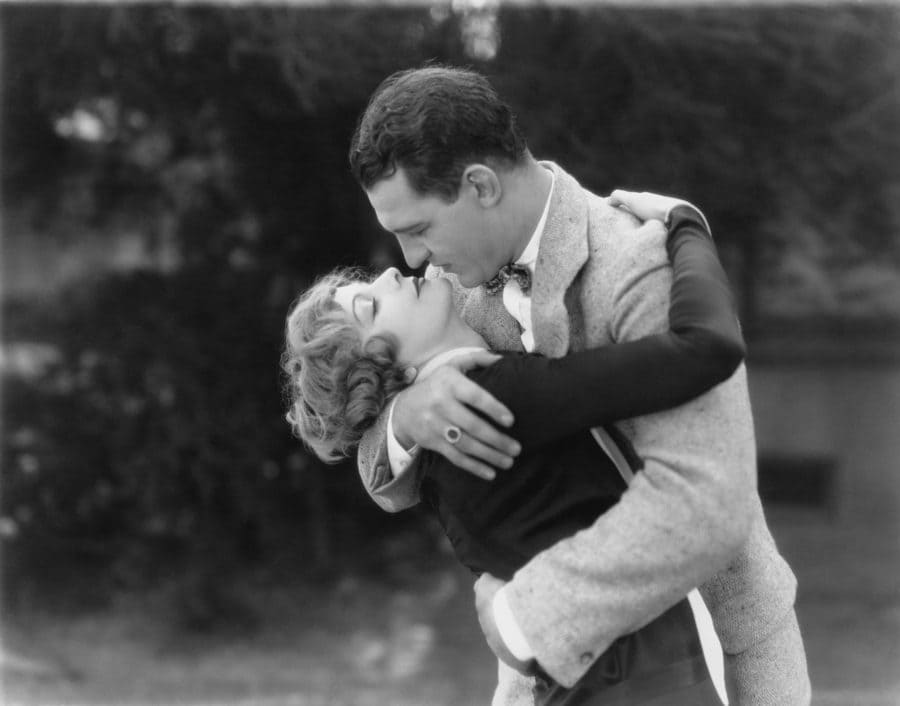 An old black and white photograph of a young couple in a passionate embrace
