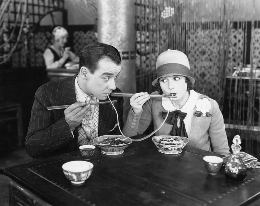 A couple sharing a noodle in a restaurant