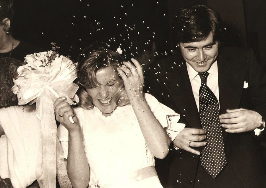A photograph of a happy bride and groom covering their heads to block the rice that was thrown at them while smiling