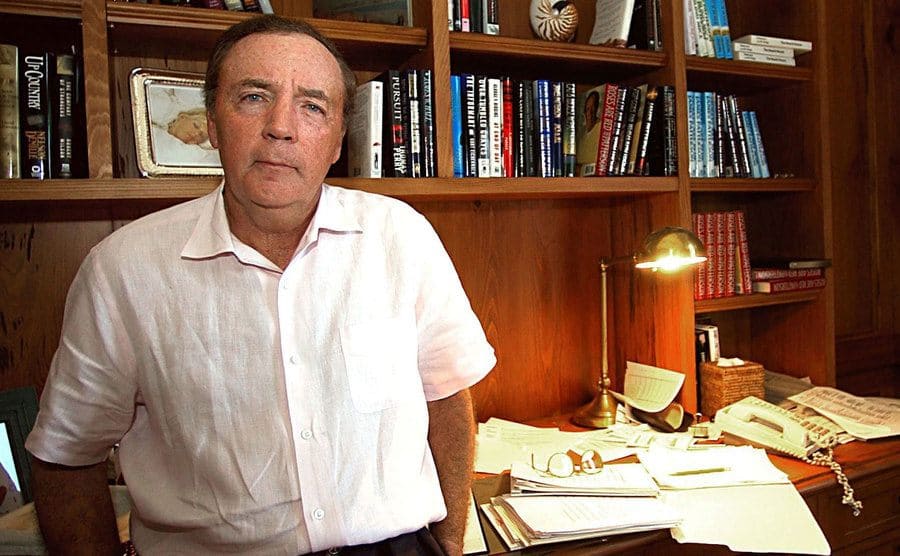 James Patterson in front of a wall with books on the shelves 