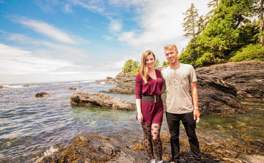 Brayden and Laura are standing on rocks covered in water 