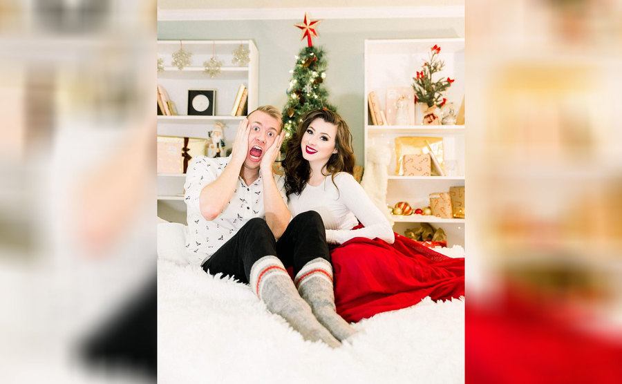 Laura and Brayden sitting on a large fluffy white bed with Christmas decorations around them 