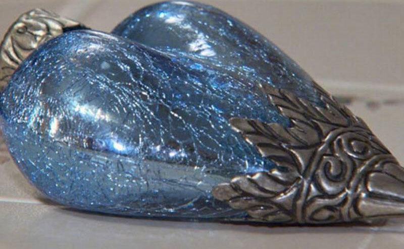 The blue and silver ornament sitting on a white tile 