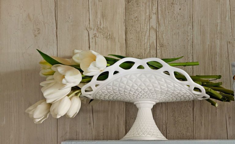 White milk glass banana stand with flowers in it