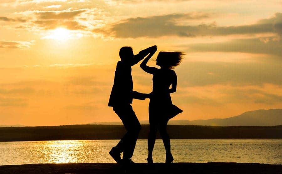 The silhouette of a couple dancing in front of a late at sunset