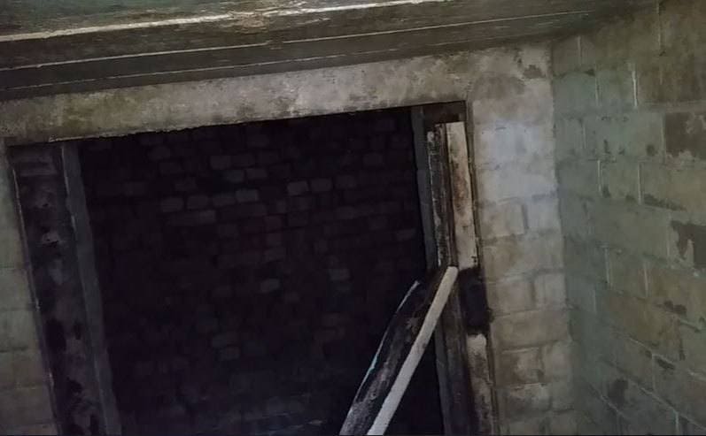 A view of the large entranceway at the bottom of the ladder which leads into another brick room 