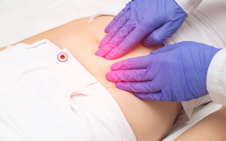 A doctor examining a woman’s abdomen 