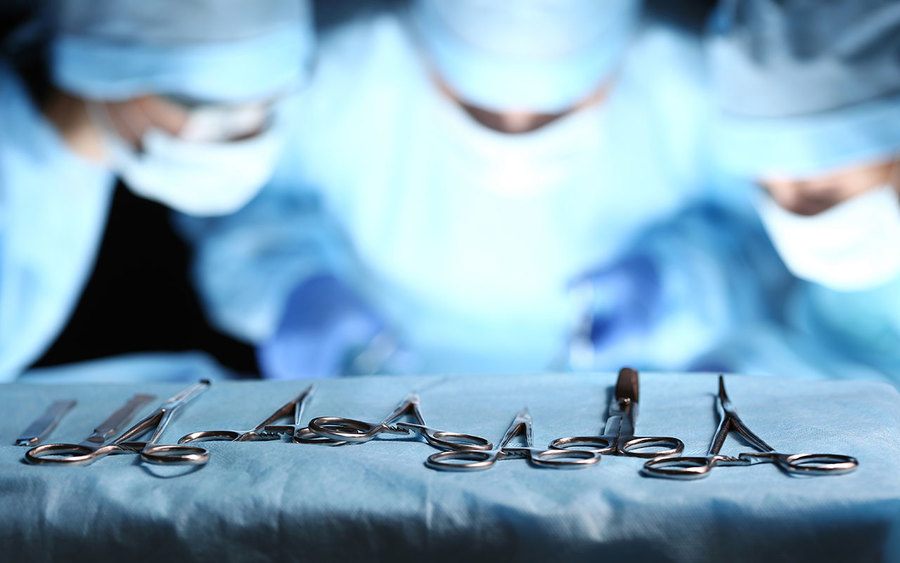A surgical tool set up lying on a table with a group of surgeons in the background 