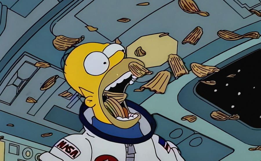 Homer Simpsons eating chips in space while they float around in an episode of ‘The Simpsons’ 