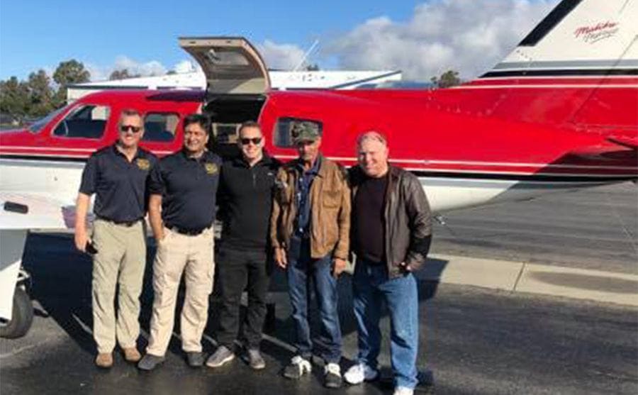 Mick with the deputy and others standing in front of a plane 