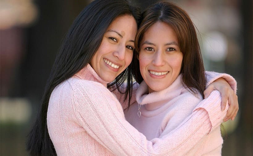 Tamara Rabi and Adriana Scott posing in pink sweaters and light jeans 