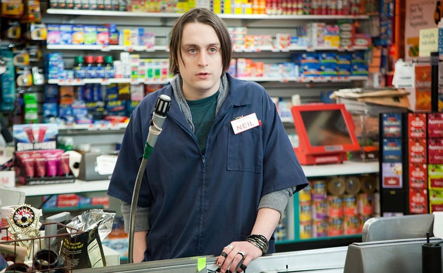 Kieran Culkin standing behind a cash register in Movie 43