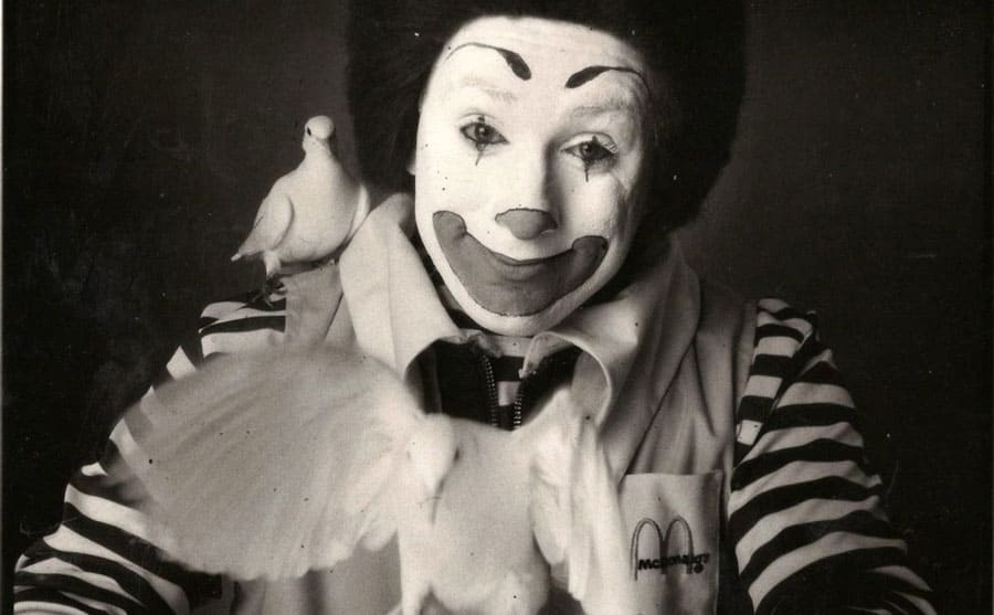 Geoffrey Giuliano as Ronald McDonald with one dove on his shoulder and one flying out of the palm of his hand 