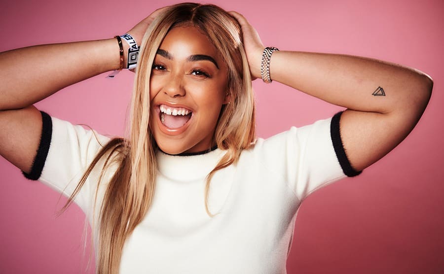 Jordyn Woods in 2017 posing in front of a pink background 