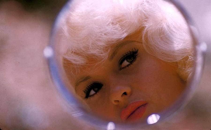A view of Jayne Mansfield looking in a small round mirror 