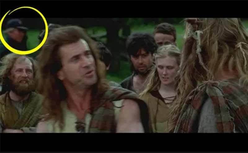 The scene from Braveheart with everyone speaking out in the open with a camera man walking behind them wearing a baseball cap 