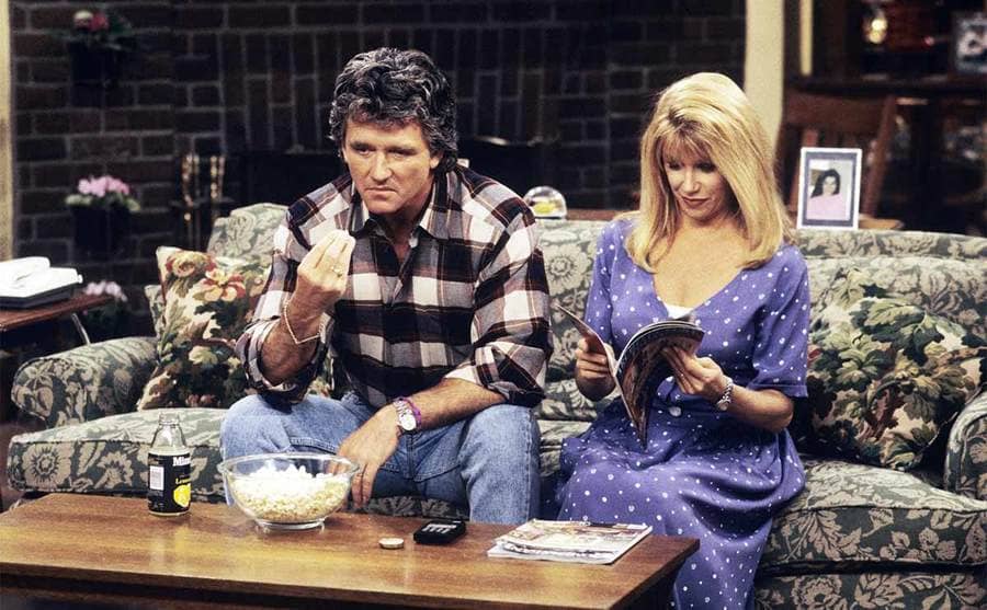 Patrick Duffy as Frank Lambert and Suzanne Somers as Carol Foster Lambert sitting on the couch on the TV show Step by Step 