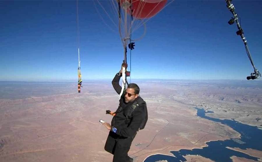David Blaine holding on to the balloons while checking his pulse 