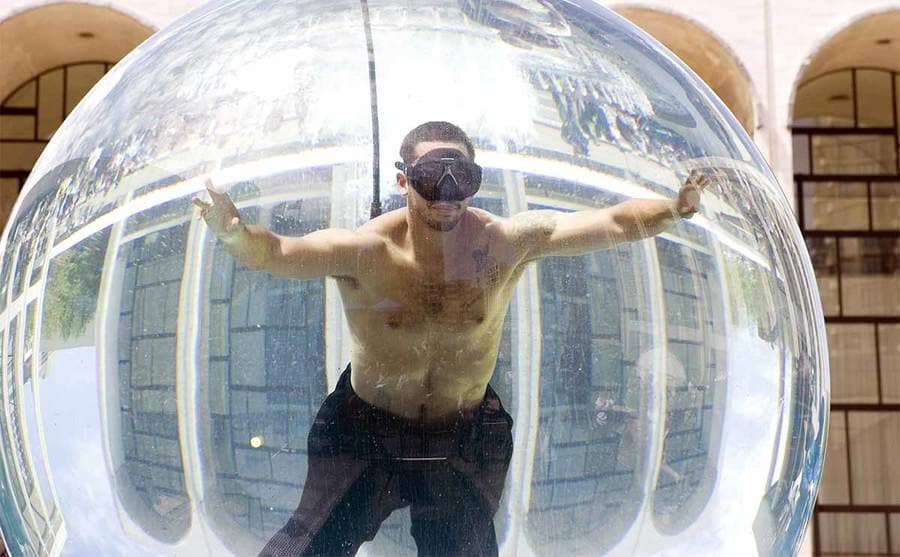 David Blaine inside of a glass bubble filled with water wearing goggles 