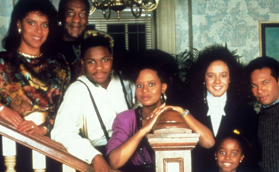 Phylicia Rashad, Bill Cosby, Malcolm-Jamal Warner, Tompsett Bledsoe, and Sabrina Le Beauf posing on the stairway on the set of the Cosby Show 