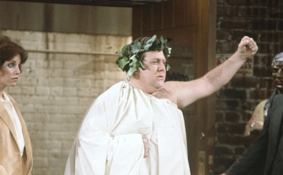George Wendt dressed in a toga and green leaves around his head in an episode of Cheers