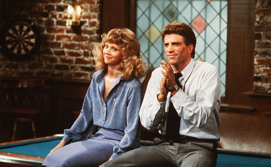Shelley Long and Ted Danson sitting on the pool table on the show Cheers