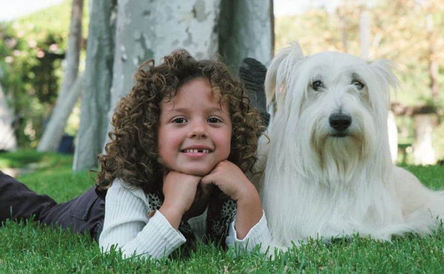Mackenzie Rosman and Happy the dog posing together in the grass underneath a tree 