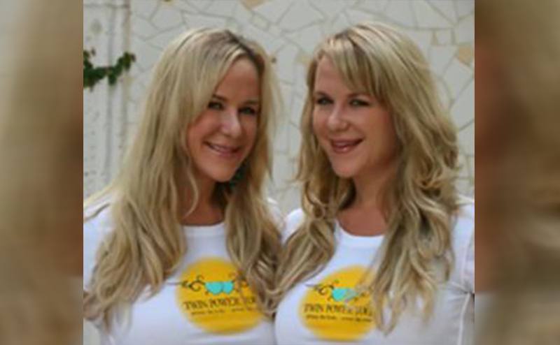 Anastasia and Alexandria Duval posing together in their yoga studio t-shirts 