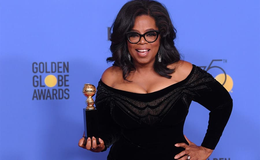 Oprah Winfrey on the red carpet holding her Golden Globe Award in 2018