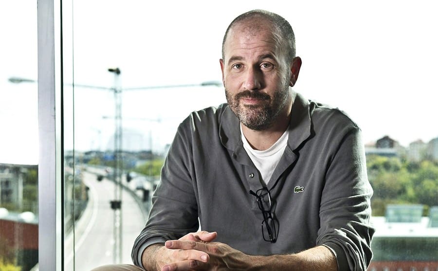 James Frey sitting on a leather stool in front of a window 