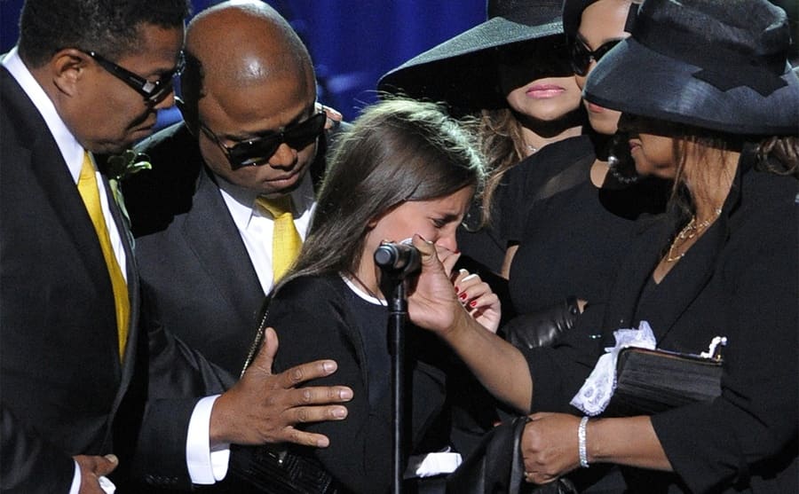 Paris Jackson being comforted by Tito, Randy, La Toya, Janet, and Rebbie Jackson on stage at Michael’s memorial service 