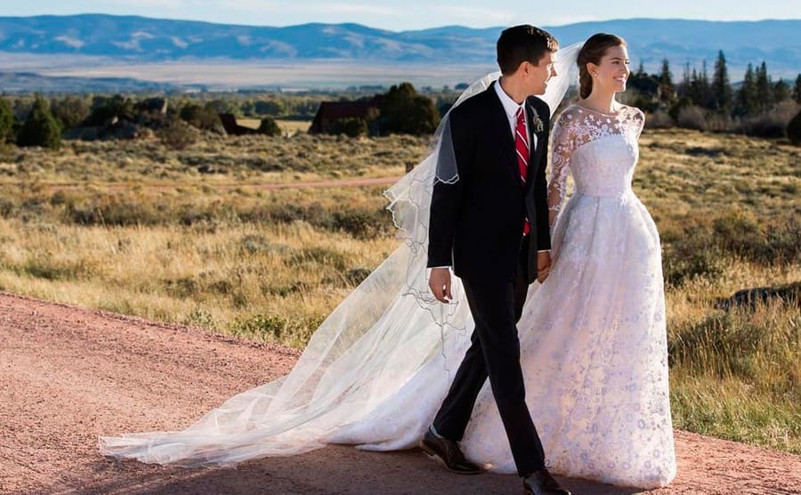 Ricky Van Veen and Allison Williams hand in hand dressed for their wedding walking down a dirt road 