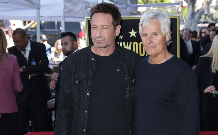 Chris Carter and David Duchovny standing on a red-carpet and hugging