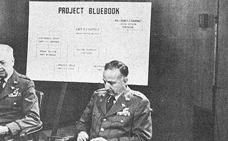 Three military men sitting beneath Project Bluebook sign