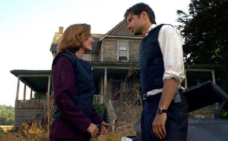 David Duchovny and Gillian Anderson standing in front of an old house