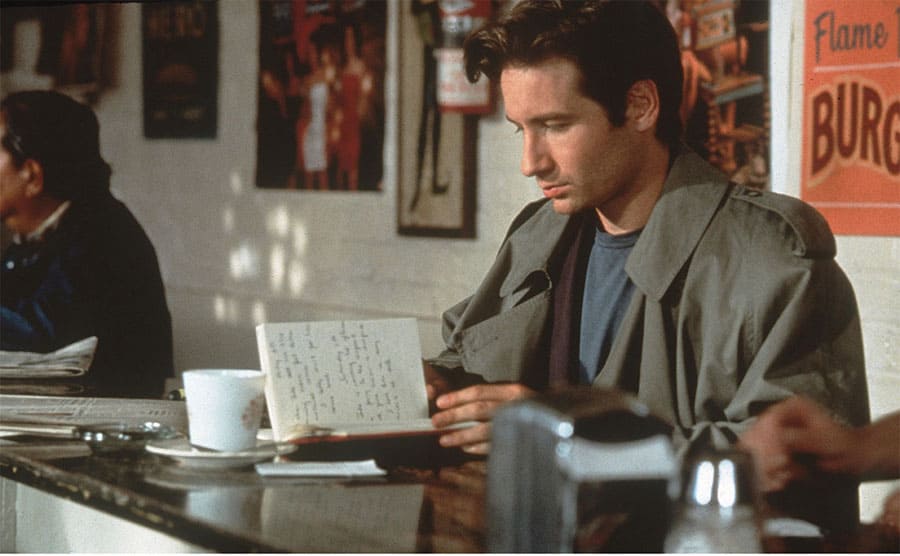 David Duchovny sitting reading in a notebook
