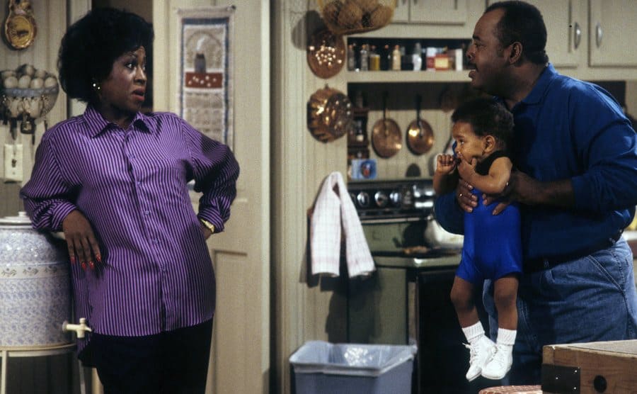 Jo Marie Payton with Reginald Vel Johnson holding Joseph or Julius Wright in the kitchen in a scene from Family Matters