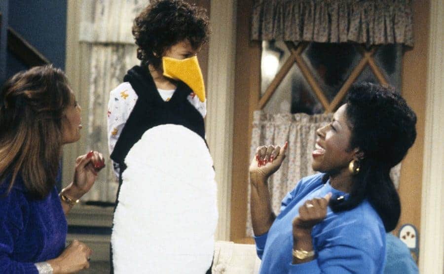 Telma Hopkins and Jo Marie Payton standing around Bryton James, who is wearing a penguin costume