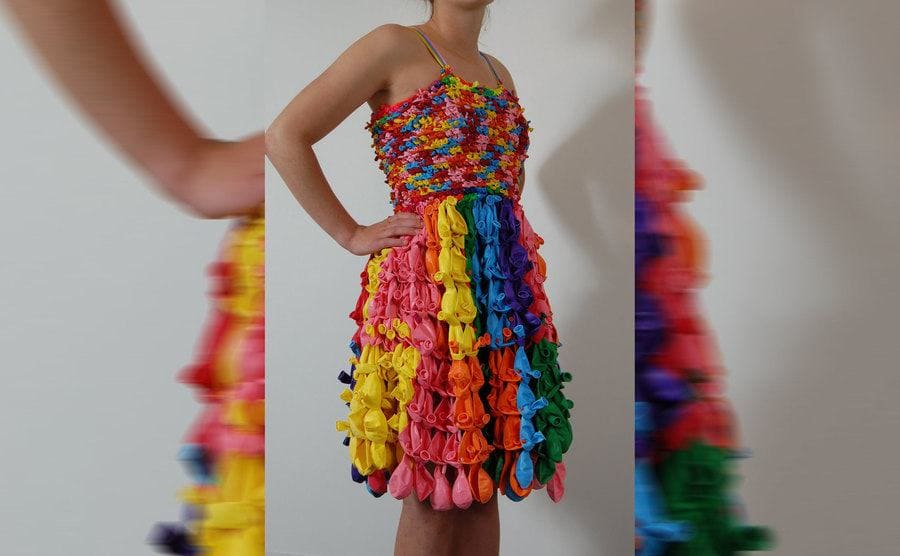 A photograph of a woman wearing a spaghetti strap dress made out of balloons without air 