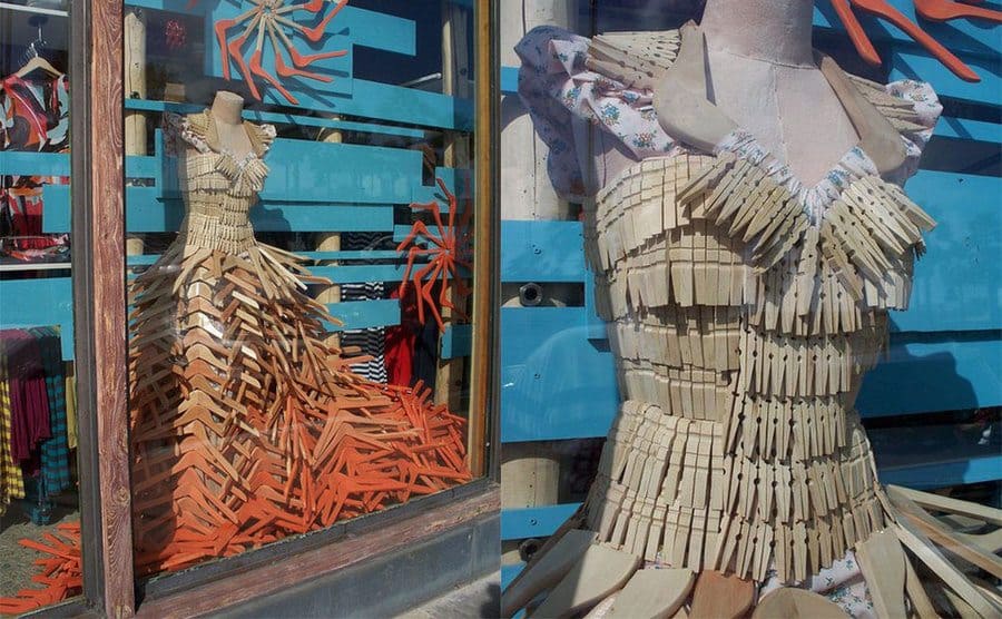 A long dress made out of clothespins on the top and hangers from light brown to a darker red-brown fading down the dress / A close-up photograph of the top of the dress made with clothespins and hangers around the shoulders 
