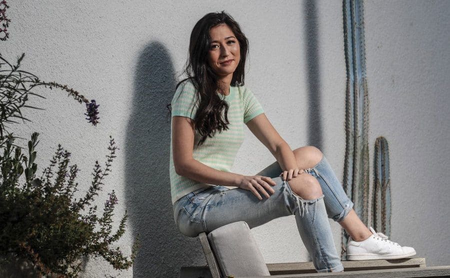 Mina Kimes sitting on a chair wearing jeans and sneakers