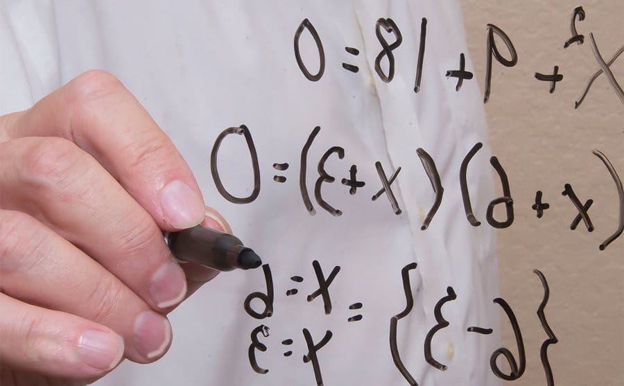 A man’s handwriting a mathematic problem on a board