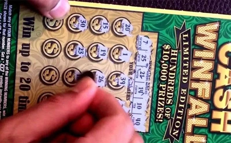 A man’s hand scratching a lottery ticket