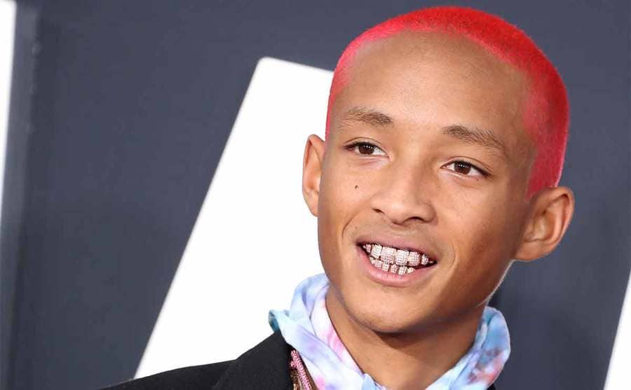 Jaden Smith with diamonds in his teeth and bright pinkish red hair on the red carpet 