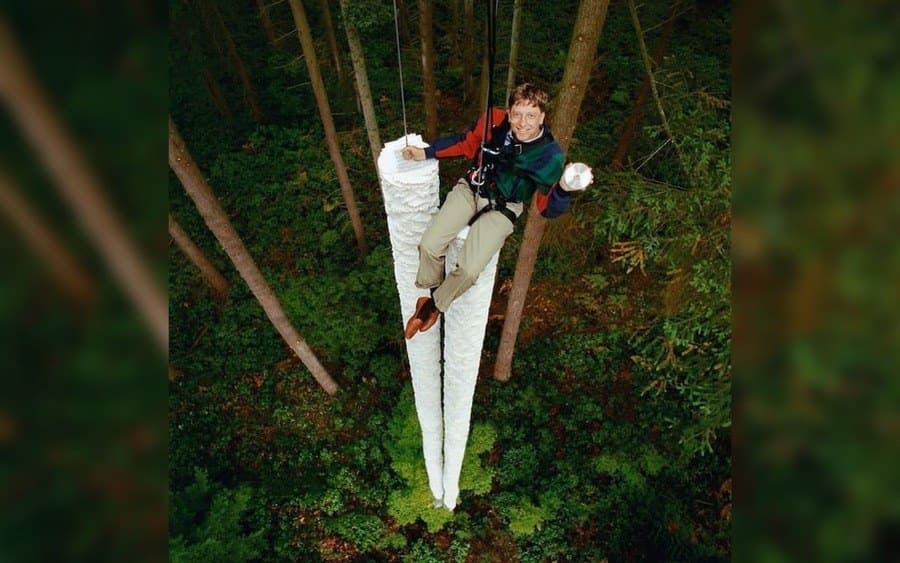 Bill Gates above two massive piles of paper stacked like a tree