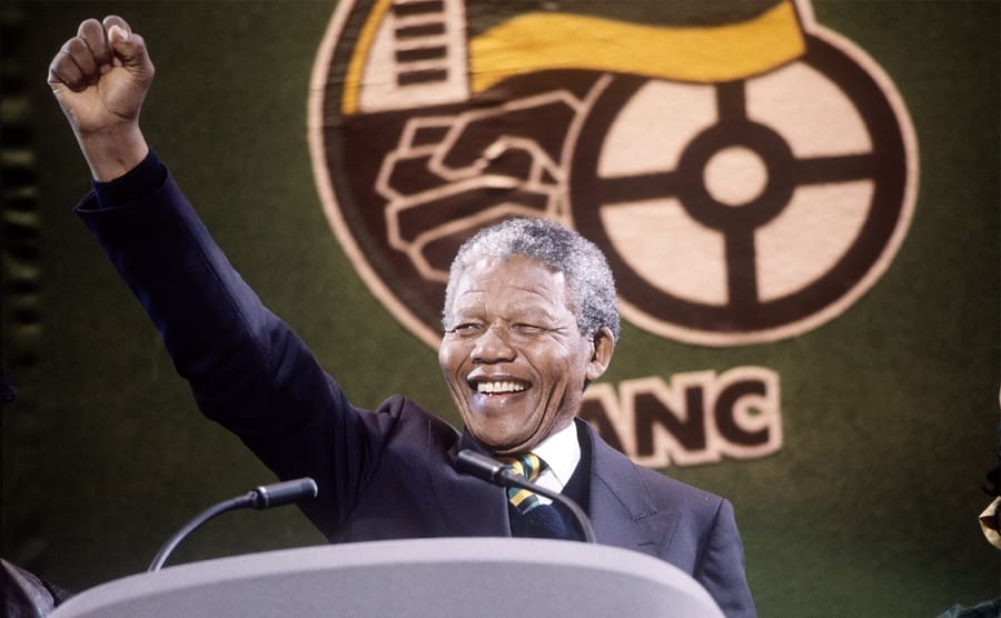 Nelson Mandela with his fist raised behind a podium in 1990