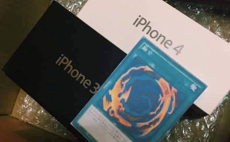 A box containing an iPhone 3, an iPhone 4, and a yu-gi-oh fushion card.