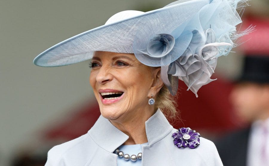 Princess Michael of Kent smiling at an event in a large hat and shawl jacket 